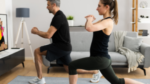 A man and a woman doing a workout in their living room.